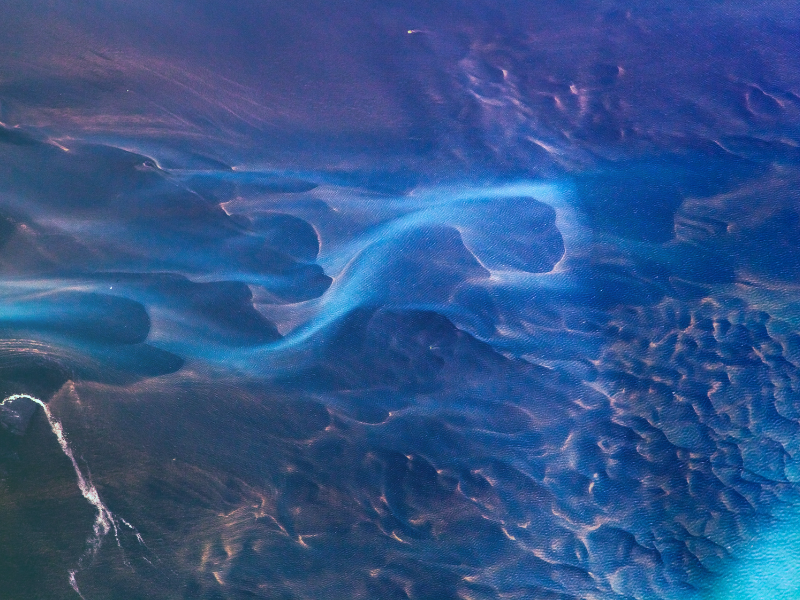 Abstract blue and purple fluid texture with glowing wave-like patterns and organic shapes.