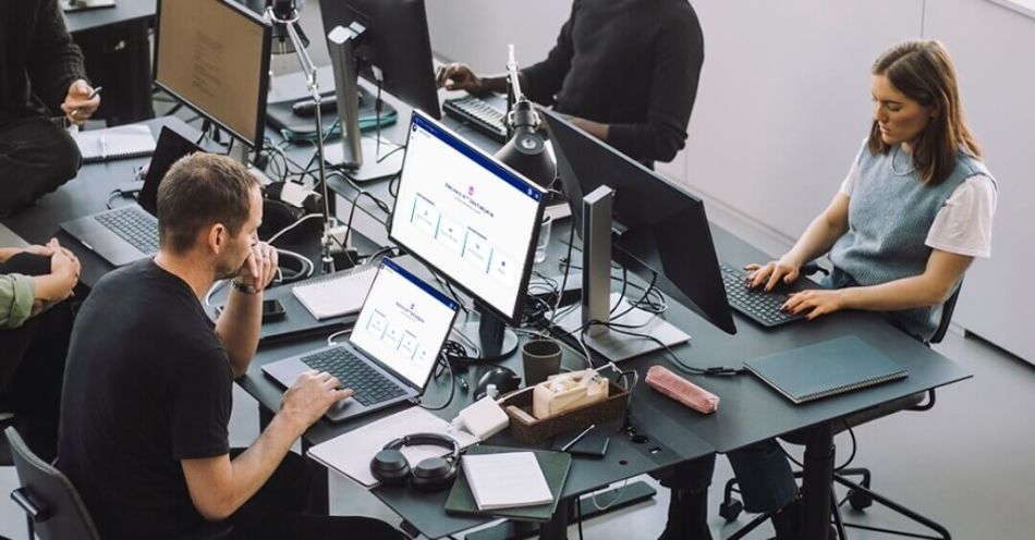 A team working in an office environment with multiple computer screens